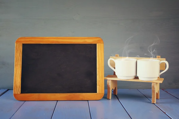 Kaffeetassen neben leerer Tafel — Stockfoto