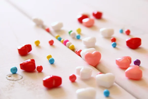 Czerwone, różowe i białe serca kształcie cukierków na drewnianym stole. — Zdjęcie stockowe