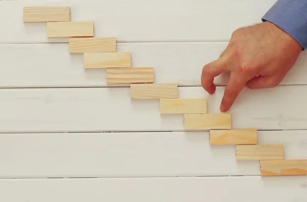 Male hand building ladder from domino bricks — Stock Photo, Image