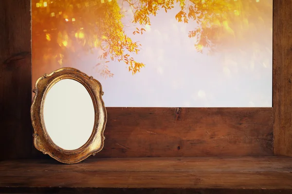 Quadro em branco velho dourado na soleira da janela de madeira . — Fotografia de Stock