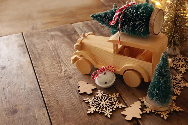 Wooden car carrying a christmas tree on wooden floor