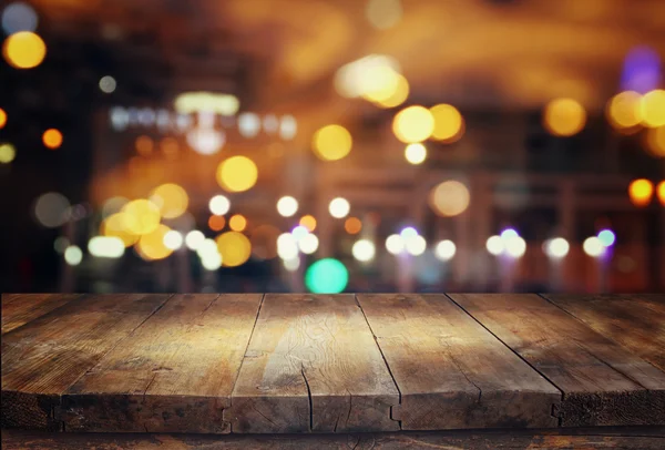 Wooden table in front of abstract blurred restaurant lights — Stock Photo, Image