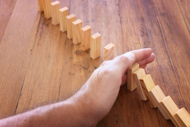 Domino etkisini durduran erkek eli görüntüsü. yönetici ve risk kontrol kavramı