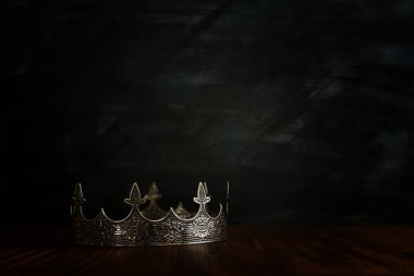 Tahta masanın üzerindeki güzel kraliçe ve kral tacının gösterişsiz görüntüsü. Eski model filtrelenmiş. fantezi ortaçağ dönemi