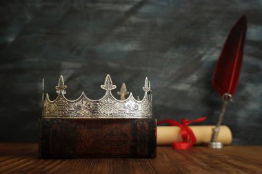 Güzel kraliçe / kral tacının gösterişsiz görüntüsü, eski kitaplar ve ahşap masanın üzerine tüy kalem. fantezi ortaçağ dönemi