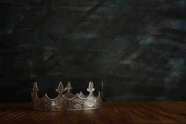 Tahta masanın üzerindeki güzel kraliçe ve kral tacının gösterişsiz görüntüsü. Eski model filtrelenmiş. fantezi ortaçağ dönemi