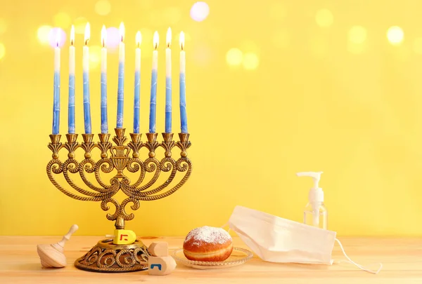 犹太节日光明节与Menorah 传统的Candelabra Donut Wooden Dreidel 纺纱顶部 的图像 头孢病毒的预防概念 医疗面罩和清洁剂凝胶 — 图库照片