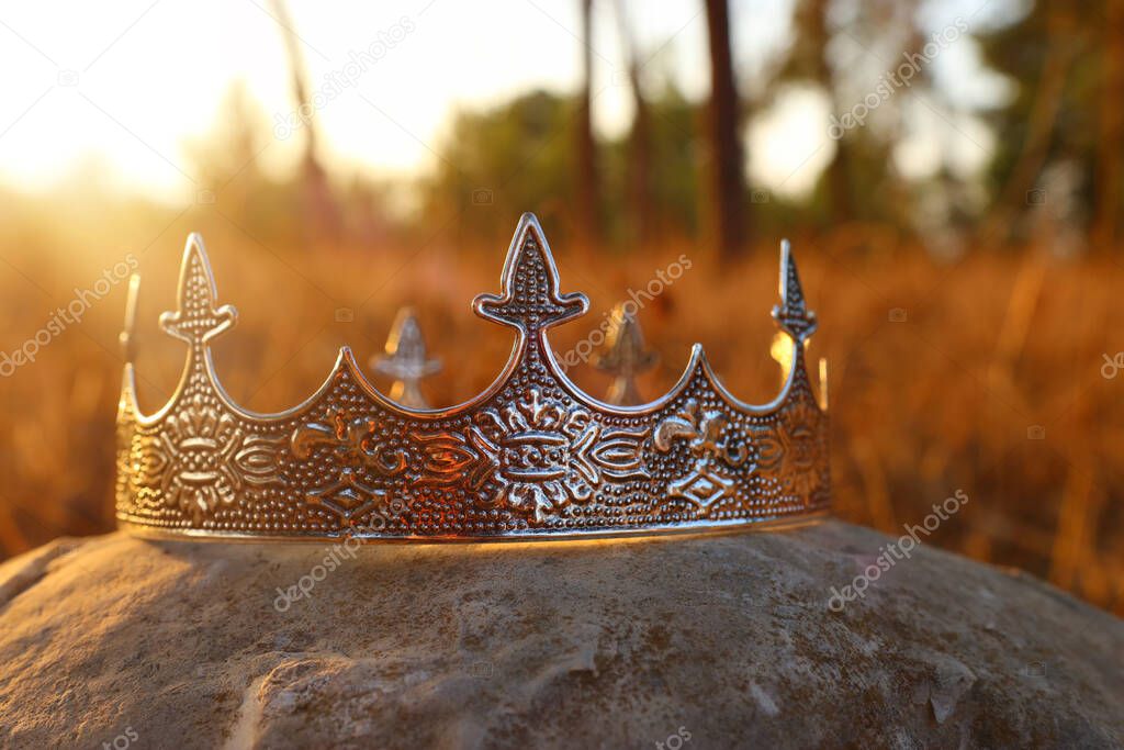 mysterious and magical photo of silver king crown in the England woods over stone. Medieval period concept.