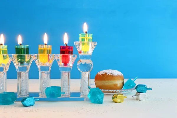 image of jewish holiday Hanukkah background with crystal menorah (traditional candelabra) and colorful oil candle