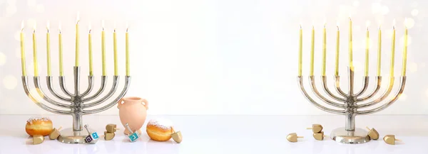 Image of jewish holiday Hanukkah with menorah (traditional Candelabra), donut and wooden dreidel (spinning top)