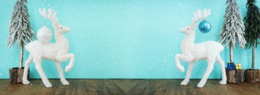 Süslemeli Noel ağacı resmi ve pastel mavi arka planda beyaz geyik.