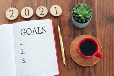 Üst görünüm iş konsepti 2021 gol listesi, defter, ahşap masa üzerinde kahve