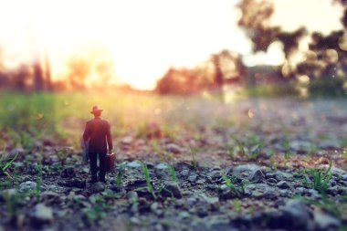 Gün batımında yalnız yürüyen gizemli bir adamın gerçeküstü görüntüsü.