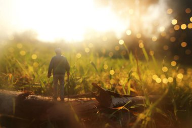 Gün batımında tarlada yalnız yürüyen gizemli bir adamın gerçeküstü görüntüsü.