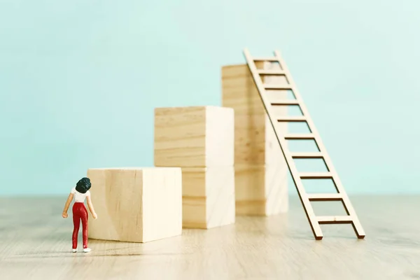 business concept picture of challenge. woman stands on the edge of a high wall and passes the gap by placing a ladder. Problem solving and decision making.