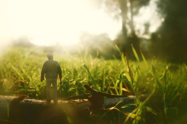 Gün batımında tarlada yalnız yürüyen gizemli bir adamın gerçeküstü görüntüsü.