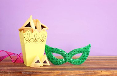 Ahşap masa ve mor arka plan üzerine Purim kutlaması konsepti (Yahudi karnavalı tatili)