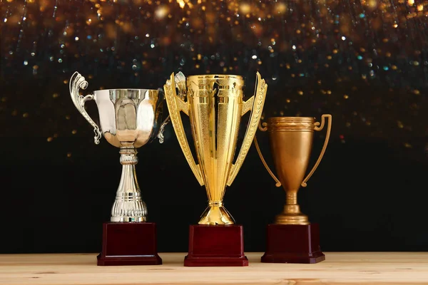 image of silver and gold trophy over wooden table and dark background, with abstract shiny lights