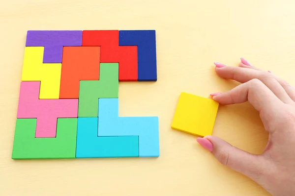 Mano Mujer Sosteniendo Rompecabezas Cuadrado Tangram Sobre Mesa Madera Pastel — Foto de Stock