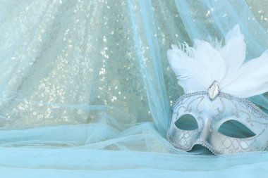 Altın ve mavi şifon arka planda zarif ve narin beyaz Venedik maskesi.