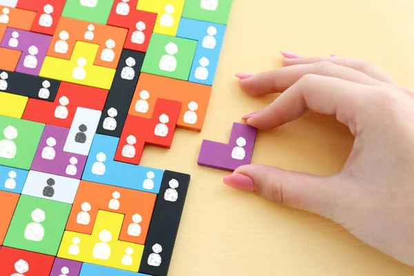 image of tangram puzzle blocks with people icons over wooden table ,human resources and management concept