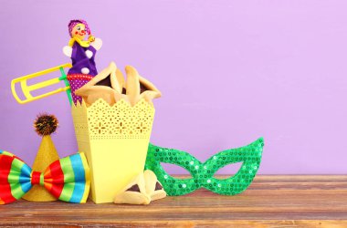 Ahşap masa ve mor arka plan üzerine Purim kutlaması konsepti (Yahudi karnavalı tatili)