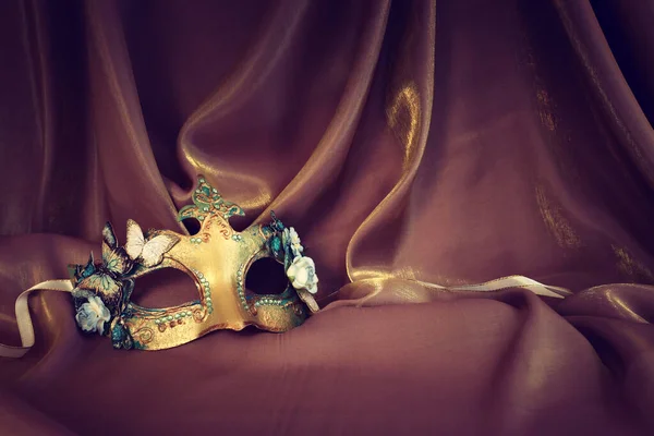 金の絹の背景にエレガントで繊細なヴェネツィアのマスクの写真 — ストック写真