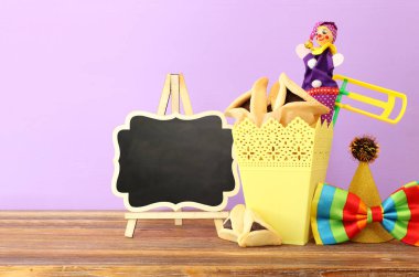 Ahşap masa ve mor arka plan üzerine Purim kutlaması konsepti (Yahudi karnavalı tatili)