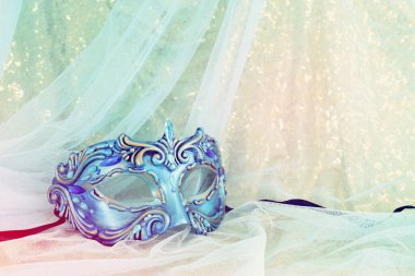 Altın ve mavi şifon arka planda zarif ve hassas Venedik maskesinin fotoğrafı