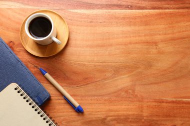Bir fincan kahve ve malzemeyle ahşap ofis masası. en üstteki görünüm
