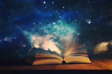 Tahta masanın üzerinde parıltılı kaplamalı açık antik kitabın sihirli görüntüsü.