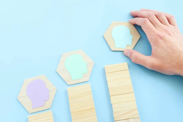 wooden blocks with people icon over blue background, building a strong team, human resources and management concept