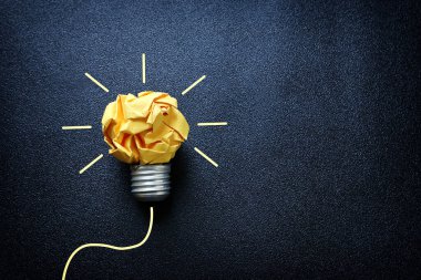 Eğitim konsepti imajı. Yaratıcı fikir ve yenilik. Kırışık kağıt siyah arkaplan üzerine ampul metaforu olarak buruşmuş kağıt