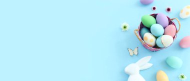 Paskalya renkli yumurtaların yanında tatlı tavşan pastel arka planda