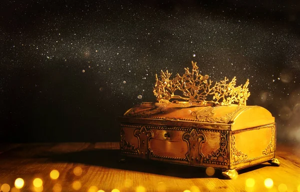 low key image of beautiful queen or king crown over gold treasure chest. vintage filtered. fantasy medieval period