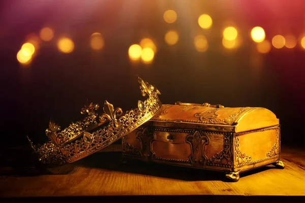 low key image of beautiful queen/king crown over gold treasure chest. vintage filtered. fantasy medieval period