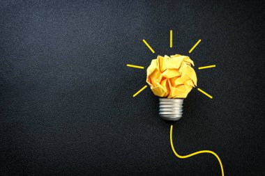 Eğitim konsepti imajı. Yaratıcı fikir ve yenilik. Kırışık kağıt siyah arkaplan üzerine ampul metaforu olarak buruşmuş kağıt