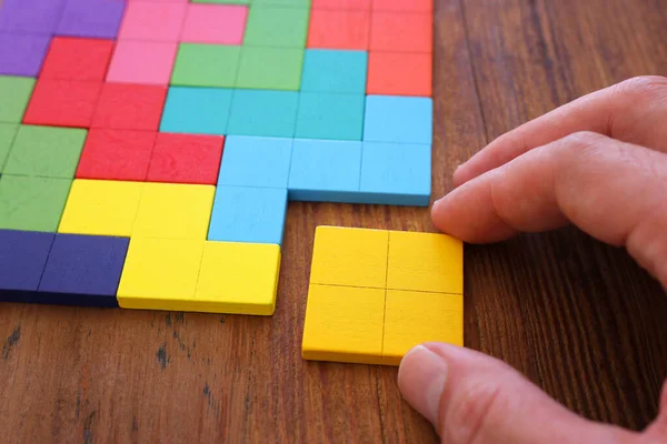 Mão Homem Segurando Quebra Cabeça Tangram Quadrado Sobre Mesa Madeira — Fotografia de Stock