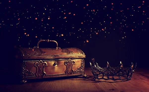 low key image of beautiful queen or king crown over gold treasure chest. vintage filtered. fantasy medieval period