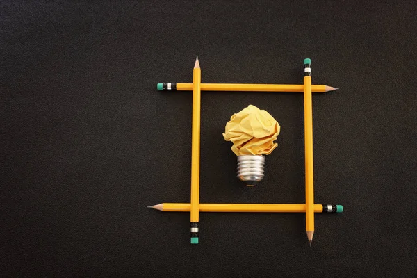 教育の概念イメージ 創造的なアイデアと革新 黒い背景の上に電球のメタファーとしての折り目のついた紙 — ストック写真