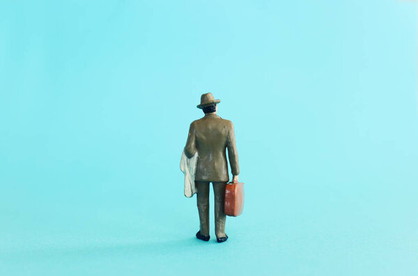 Man figurine back view over blue background