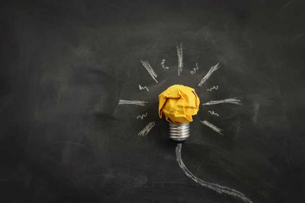 Education concept image. Creative idea and innovation. Crumpled paper as light bulb metaphor over blackboard