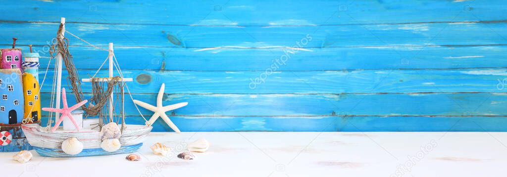 Top view of Nautical concept with sea life style objects as boat, driftwood beach houses, seashells and starfish over wooden background