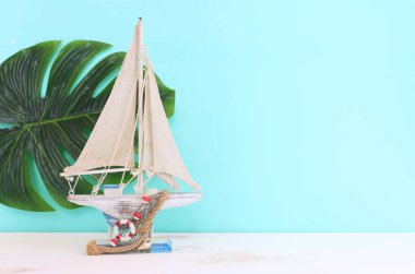 Ahşap masa ve mavi arkaplan üzerinde beyaz süs yelkenli tekne ile denizcilik kavramı
