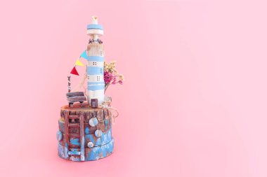 Pembe pastel arka plan üzerinde sürüklenen deniz feneriyle ilgili denizcilik kavramı