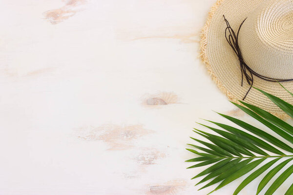 nautical concept with palm leaf, beach hat and starfish over white wooden background