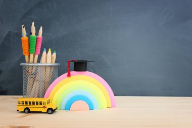 Eğitim ve okul konseptine geri dönüş. Sınıf tahtasının önündeki ahşap masanın üzerine kırtasiye kağıdı.