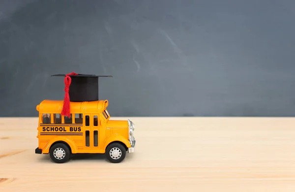 教育と学校の概念に戻ります 黄色のバス木の机の上に卒業帽子 — ストック写真
