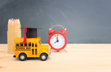 Eğitim ve okul konseptine geri dönüş. Ahşap masasında mezuniyet şapkası olan sarı otobüs.