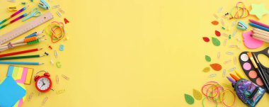 Okul konseptine geri dönelim. Pastel sarı arkaplan üzerindeki öğrenci kırtasiyesinin üst görünümü